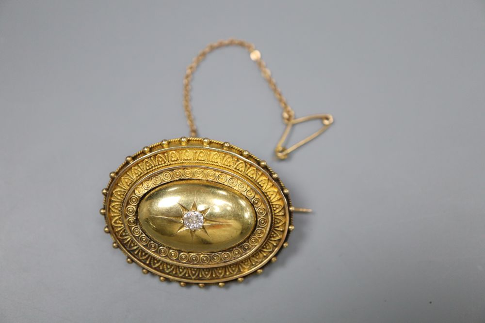 A Victorian yellow metal and diamond set oval brooch, with glazed back and safety chain, 39mm, gross 11.1 grams.